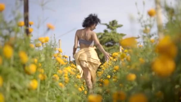 Chica feliz y despreocupada corriendo por el vibrante campo rural de flores amarillas, libertad y armonía en la naturaleza — Vídeos de Stock