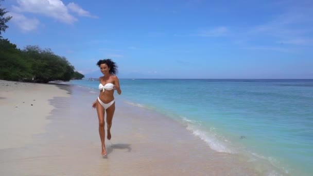 Menina feliz animado em biquíni maiô correndo na costa do oceano arenoso, ativa fins de semana tropicais no paraíso — Vídeo de Stock