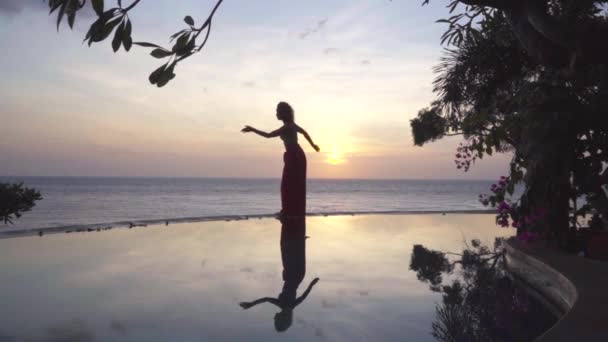Mulher de elegância solitária dançando na noite romântica perto de água, pôr do sol e reflexo silhueta feminina — Vídeo de Stock