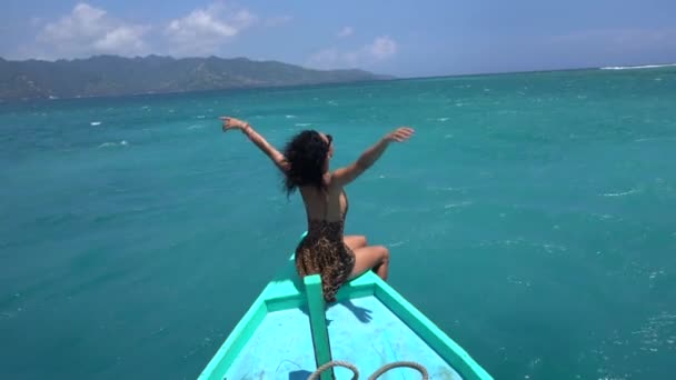 Mujer alegre sentada en el borde del barco, disfrutando del océano fresco y el viento, navegación emocionante a la isla idílica — Vídeo de stock