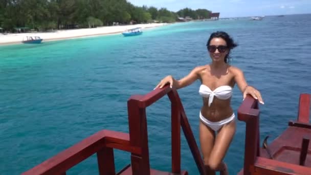Úžasné hubené brunetky dívka v bílých plavkách jít nahoru na vintage dřevěné lodi v oceánu — Stock video