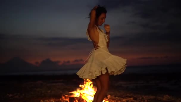 Romantic evening with a fireplace on nature with charming woman dancing, summer night entertainment — Stock Video