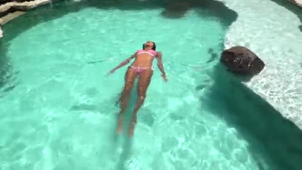 Чарівна брюнетка жіноча модель плавання в курортному басейні, відпочинок і комфорт на літні вихідні — стокове відео