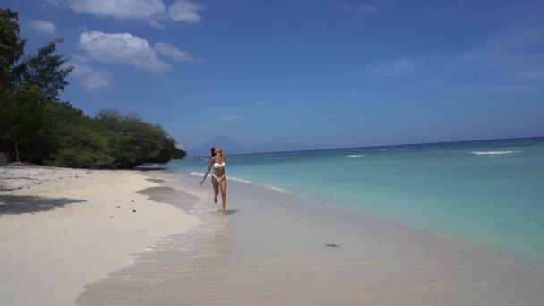 Happy pretty girl running in bikini through sandy coastline, joyful carefree exotic vacation destination — Stock Video