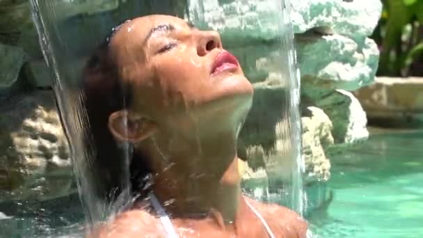 Impresionante mujer morena disfrutando de una pequeña cascada en la piscina, spa de relajación en el resort de prestigio — Vídeo de stock