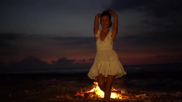 Charmig kvinna glatt dansar framför öppen spis på sandstrand, mystisk fest kväll landskap — Stockvideo