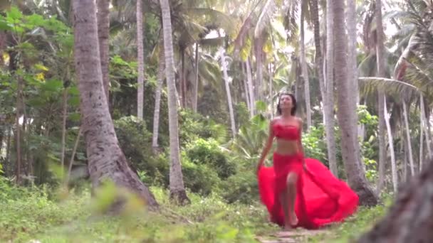 Magnífica mujer morena en falda de color rojo brillante corriendo alegremente a través de la naturaleza palmas salvajes selvas — Vídeo de stock