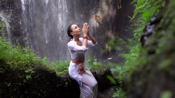 Értelmes, elegáns nő imádkozik a trópusi dzsungelben, szivárvány a vízesésben, szépség a természetben — Stock videók