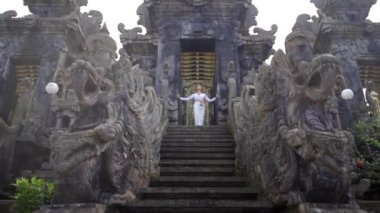 Geniş Budist tapınağının panorama manzarası, oryantal detaylar, girişte duran beyaz elbiseli kadın duası.