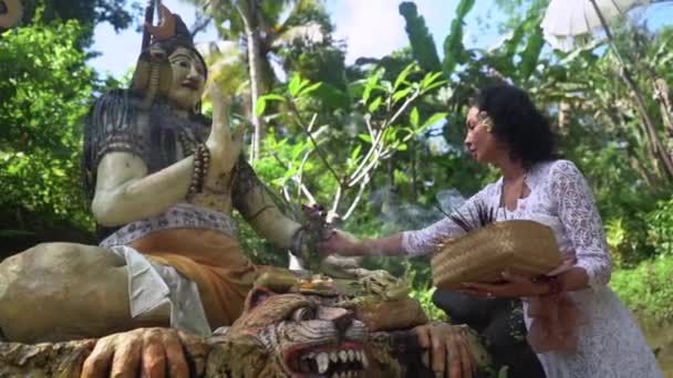 Donna che offre fiori alla scultura buddhista all'aperto, natura tropicale intorno al tempio di religione sacra — Video Stock