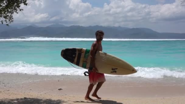 Surfeur sportif courant le long de la plage d'été transportant la planche de surf, activité de loisirs océaniques, Kuta - Indonésie - 2021 Séquence Vidéo