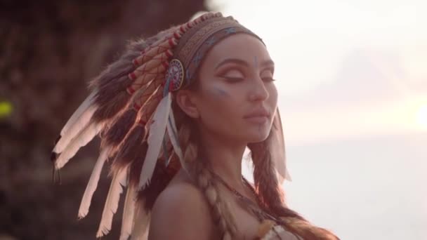 Filmes portré egy amerikai indiai nőről festett sminkkel és indiai kultúrtollas fejdísszel. — Stock videók