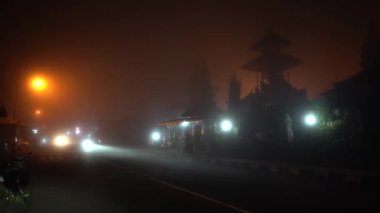 Motosiklet sisli bir şekilde dağda, gece yol boyunca gidiyor. Kalın sis ve yan görüş yüzünden görüş mesafesi çok düşük. Tehlikeli puslu otoyolda farları olan yolcu vagonu. Sisli