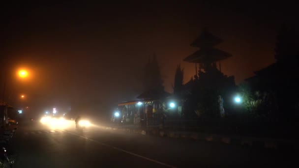 Voiture et motos conduisent dans le brouillard le long de la route en montagne, la nuit. Très mauvaise visibilité sur la voie en raison d'une épaisse brume, vue latérale. Conduites de voitures particulières avec phares dans la brume dangereuse autoroute couverte Vidéo De Stock