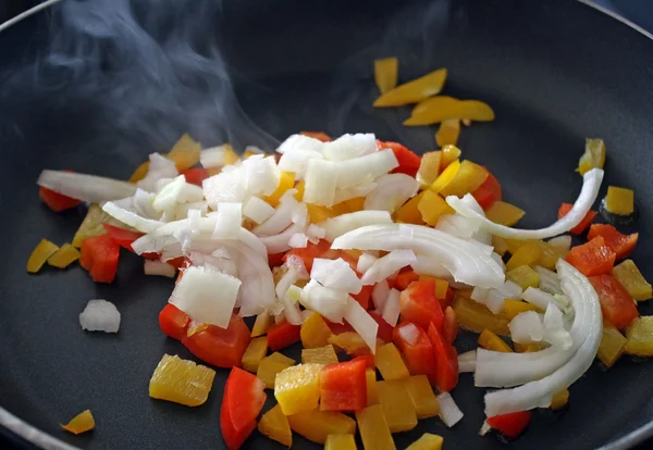 Pimentos e cebolas fritando em frigideira — Fotografia de Stock