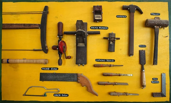 Old carpenter tools collection isolated on yellow background.