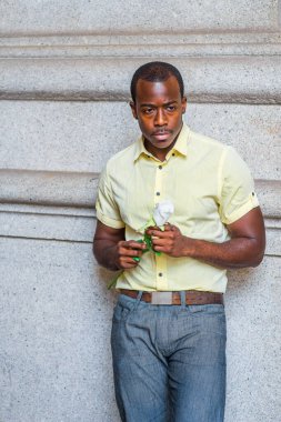 Kaşlarını çattı, aşağı baktı, genç siyah bir adam elinde beyaz bir gül tutuyordu, duvarın yanında duruyordu, düşüncelere dalmıştı.