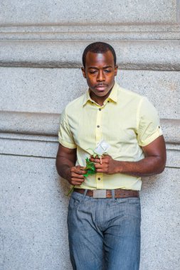 Kaşlarını çattı, aşağı baktı, genç siyah bir adam elinde beyaz bir gül tutuyordu, duvarın yanında duruyordu, düşüncelere dalmıştı.