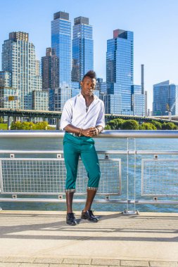 Kentsel Gündelik Moda. Beyaz, uzun kollu gömlekli, yeşil pantolonlu, deri ayakkabılı, Mohawk tıraşlı genç bir adam iş yerinin önünde duruyor ve kendine güvenen bir şekilde sana bakıyor..