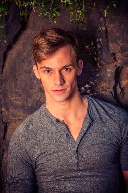 Genç Yakışıklı Adam 'ın portresi. Filtre Efekti. Genç bir adam sıradan giyiniyor, Autum 'da kayaların yanında duruyor.