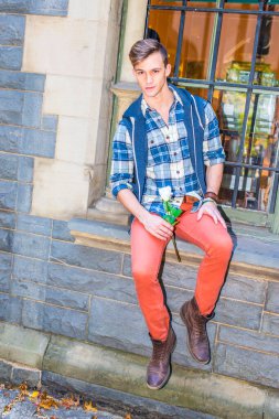 Şablon gömlek, kapüşonlu yelek, kırmızı kot pantolon ve kahverengi deri ayakkabı giymiş genç bir adam pencerenin kenarında oturuyor, elinde beyaz bir çiçek, seni bekliyor.