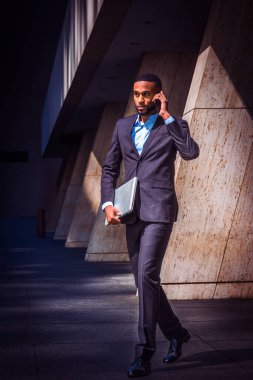 Cep telefonuyla konuşan sakallı genç Afrikalı-Amerikalı işadamı seyahat, New York, dizüstü bilgisayar, ofis binadan çıkıp taşıyan deri ayakkabılar, siyah takım elbise çalışma.