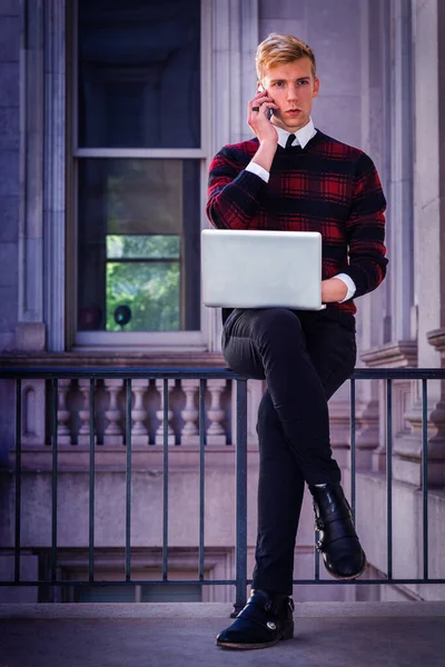 New York 'ta çalışan genç bir adam. Örgü örülü süveter, siyah pantolon, deri ayakkabı giyen, ofis binasında parmaklıklar üzerinde oturan, dizüstü bilgisayarla çalışan, cep telefonuyla konuşan genç bir adam.