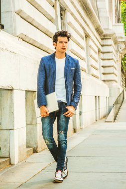 Ciddi bir Avrupalı üniversite öğrencisi New York 'ta okuyor. Mavi ceket, kot pantolon, spor ayakkabı, dizüstü bilgisayar tutan eller, kampüste düşünen genç bir adam. Gündelik Moda.