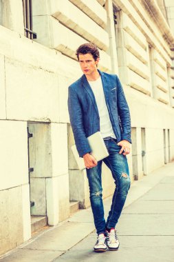 Ciddi bir Avrupalı üniversite öğrencisi New York 'ta okuyor. Mavi ceket, kot pantolon, spor ayakkabı, dizüstü bilgisayar tutan eller, kampüste düşünen genç bir adam. Gündelik Moda.