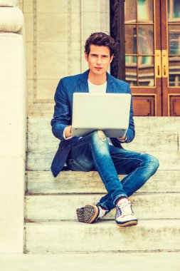 Avrupalı üniversite öğrencisi New York 'ta okuyor. Mavi ceketli, kot pantolonlu, spor ayakkabılı, kampüste merdivenlerde oturan, bacak bacak üstüne atan, okuyan, dizüstü bilgisayarda çalışan bir genç..
