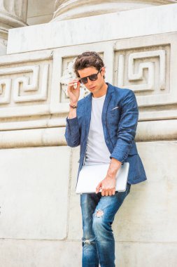 Avrupalı üniversite öğrencisi New York 'ta okuyor. Mavi ceketli, beyaz gömlekli, kot pantolonlu, güneş gözlüklü, dizüstü bilgisayarlı, kampüste köşesinde duran, aşağıya bakıp,