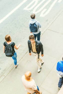 New York 'ta seyahat eden, siyah ceketli, sarı pantolonlu, yabancıların yanından geçen, kaldırımda yürüyen, seni arayan Avrupalı bir adam. Üst Manzara. Arkadaşlık arayan yalnız adam konsepti