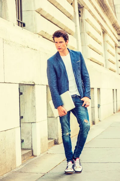 Ciddi bir Avrupalı üniversite öğrencisi New York 'ta okuyor. Mavi ceket, kot pantolon, spor ayakkabı, dizüstü bilgisayar tutan eller, kampüste düşünen genç bir adam. Gündelik Moda.