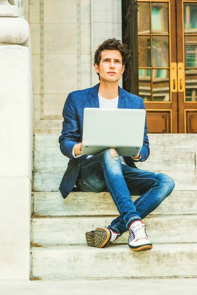 Avrupalı üniversite öğrencisi New York 'ta okuyor. Mavi ceketli, kot pantolonlu, spor ayakkabılı, kampüste merdivenlerde oturan, bacak bacak üstüne atan, okuyan, dizüstü bilgisayarda çalışan bir genç..
