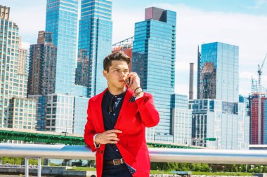 Seyahat eden bir iş adamı, New York 'ta çalışıyor. Kırmızı ceket, mavi yakalı gömlek, pantolon, iş yerinin dışında yüksek binalarla meşgul bir genç adam cep telefonuyla konuşuyor.