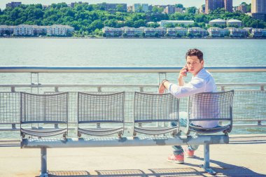 Senin için boş sandalyeler. Beyaz gömlekli, kot pantolonlu, spor ayakkabılı, New Jersey 'de Hudson Nehri' nin kenarında oturan genç yalnız bir adam, yüzünü New Jersey 'e dönmüş, telefon görüşmesi yapıyor, seni bekliyor. Boşluğu Kopyala