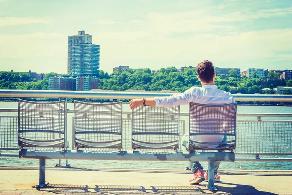 Empty Chairs for You. lonely man seeking friendship. Wearing white shirt, jeans, sneakers, a young lonely guy sitting by Hudson River in New York, facing New Jersey, waiting for you. Copy Space.