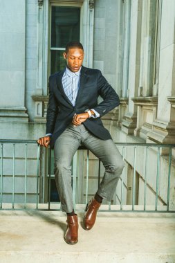 Seni bekleyen bir adam var. Siyah ceketli, gri pantolonlu, kahverengi deri ayakkabılı, Afrika kökenli Amerikalı işadamı eski tarz bir ofiste korkuluklara oturmuş, kol saatine bakıyor. Vakit nakittir.