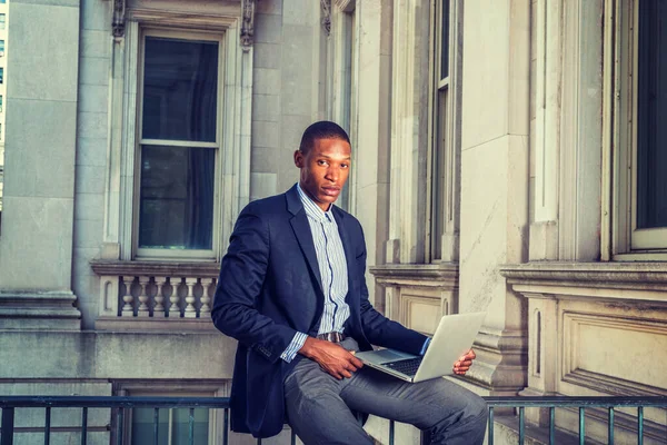 New York 'ta çalışan Afrikalı Amerikalı iş adamı. Siyah ceketli, korkuluklarda oturan eski tarz ofis binası, okuyan, düşünen, dizüstü bilgisayarla çalışan bir adam..