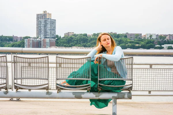 Yalnız kız seni özlüyor. Açık mavi süveter, yeşil etek, New Jersey 'in karşısında Hudson Nehri' nin kenarında sıradan bir şekilde oturan Amerikalı bir kadın, yorgun görünüyor, düşüncelere dalmış.