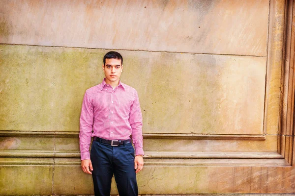 Üniversite öğrencisinin portresi. Sıradan erkek modası. Kırmızı desenli, uzun kollu gömlekli, siyah pantolonlu, klasik tarz duvara karşı duran, kendinden emin bir şekilde ileriye bakan genç bir adam. Boşluğu kopyala