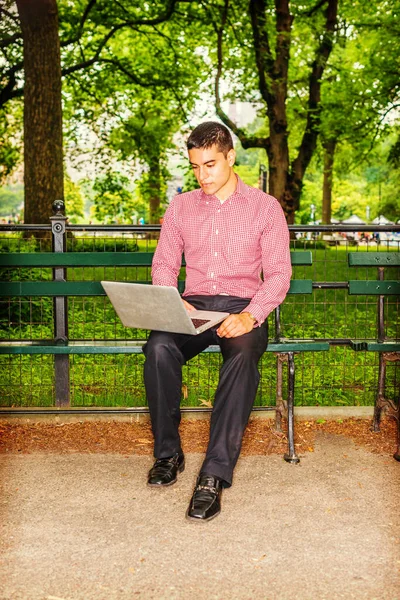 外面工作的人穿着红色 白色图案的衬衫 黑色裤子 一个年轻的大学生坐在树下的椅子上 在笔记本电脑上工作 日常生活中的技术 — 图库照片