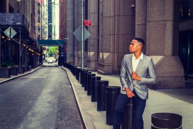 Afrikalı Amerikalı iş adamı çalışıyor, New York 'ta seyahat ediyor. Bir üniversite öğrencisi sokakta, ofis binasının dışında metal sütunun üzerinde oturmuş düşünüyor. Arka planda çalışan küçük bir araba. Filtrelenmiş etki.