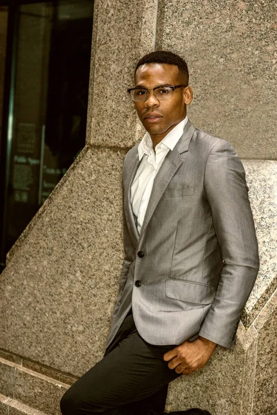 New York 'ta çalışan Afrikalı Amerikalı iş adamı. Gri ceketli, gözlüklü, siyahi üniversite öğrencisi ofisin dışında köşesinde duruyor, üzgün, düşünceli, düşüncelere dalmış. Renkli filtrelenmiş efekt