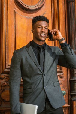 New York 'ta çalışan Afrikalı Amerikalı iş adamı. Şık bir ceket, siyah kravat, dizüstü bilgisayar, küçük keçi sakallı genç adam, klasik tarzda kapı eşiğinde duruyor, telefonla arıyor.