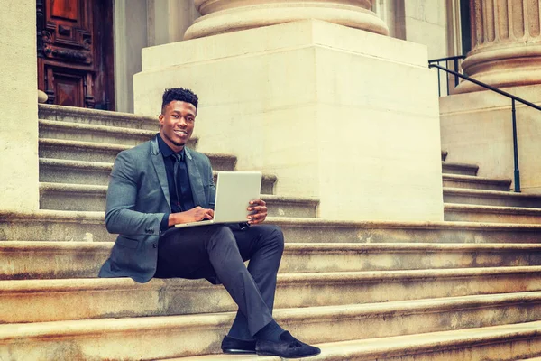 New York 'ta çalışan Afrikalı Amerikalı iş adamı. Şık bir ceket, kravat, ofis binasının dışındaki merdivenlerde oturan, gülümseyen, dizüstü bilgisayarla çalışan siyah bir adam. Filtrelenmiş etki