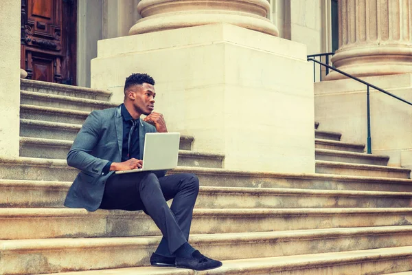New York 'ta çalışan Afrikalı Amerikalı iş adamı. Klasik ofis binasının dışındaki merdivenlerde oturan genç siyahi adam, çenesine dokunan, düşünen, dizüstü bilgisayarla çalışan. Filtrelenmiş etki