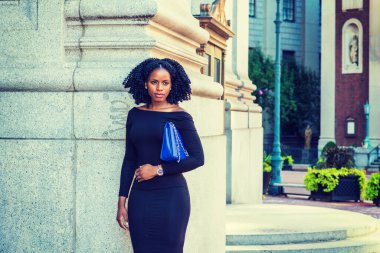 New York 'ta çalışan Afrikalı Amerikalı iş kadını. Uzun kollu, ince, omuzlu, kolunun altında mavi çanta taşıyan, örgülü saç stili sokakta duran,