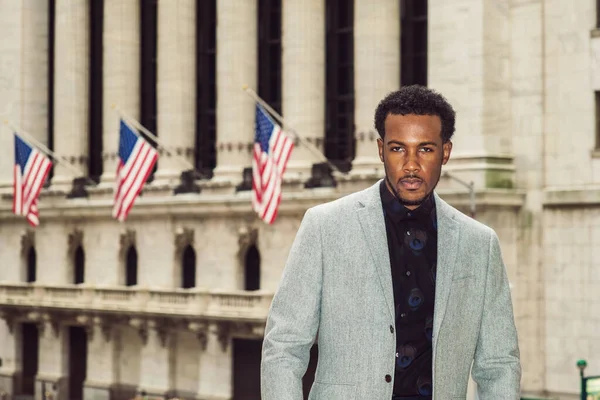 Afrikalı Amerikalı iş adamı seyahat ediyor, New York 'ta çalışıyor. Gri desenli spor ceket giyen, sakallı genç siyahi adam caddede ofis binasının yanında duruyor, ileriye bakıyor..