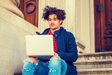 Çilli yüzlü, kıvırcık saçlı, kapüşonlu mavi ceketli, mahvolmuş kotlu, New York 'ta kampüsün merdivenlerinde oturan, okuyan, dizüstü bilgisayarda çalışan Amerikalı bir üniversite öğrencisi.. 